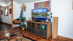 Ein Wohnzimmer mit Fernseher, Holzschrank und einem Bild an der Wand.