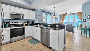 A modern kitchen with white cabinets, stainless steel appliances, and a large island. - Gulf-front corner unit. 5th floor. Beach service during season! (Fort Walton Beach)