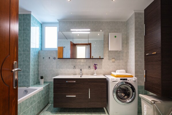 Un baño moderno con lavadora integrada, bañera y tocador con espejo.