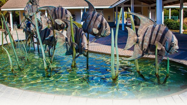 A pool area with large fish sculptures and a building in the background.
