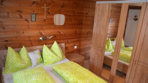 Una habitación de cabaña de madera con una cama, un espejo y un armario de madera.