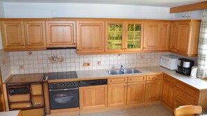 Una cocina compacta con armarios de madera, horno empotrado, lavavajillas y microondas.