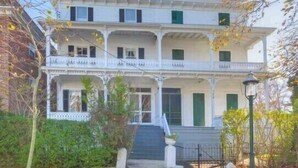 A two-story building with a balcony, a front entrance with steps, and a street lamp. - Completely Renovated Victorian across from Congress Hall (Cape May)