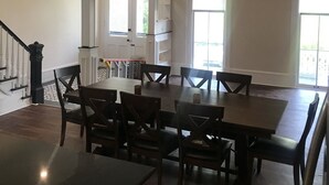 A spacious dining area with a high ceiling, large windows, and a staircase leading to another level. - Completely Renovated Victorian across from Congress Hall (Cape May)