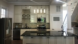 A modern kitchen with white cabinetry, a granite countertop, stainless steel appliances, and pendant lighting. - Completely Renovated Victorian across from Congress Hall (Cape May)