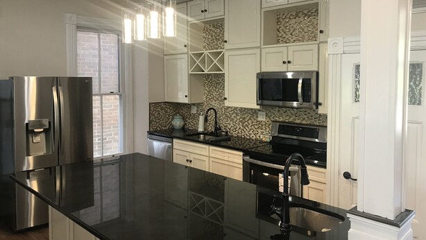 A modern kitchen with white cabinets, a stainless steel refrigerator, a microwave, and a black countertop. - Completely Renovated Victorian across from Congress Hall (Cape May)