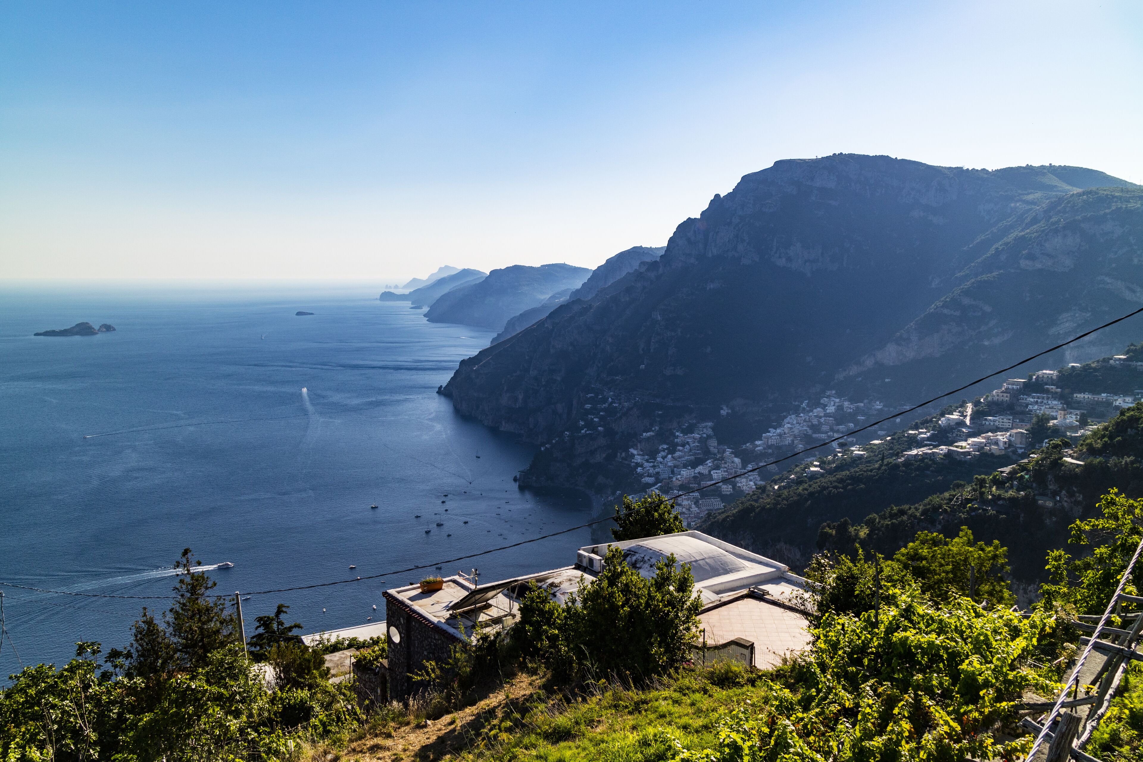 Eine Küstenlandschaft mit Blick auf das Meer, einen Berg und ein Gebäude mit flachem Dach.