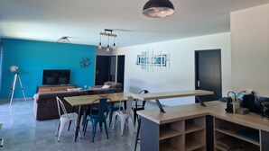 A modern living room with a wooden dining table, blue walls, and a black pendant light.