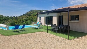 A house with a pool, outdoor seating, and a view of a hillside.
