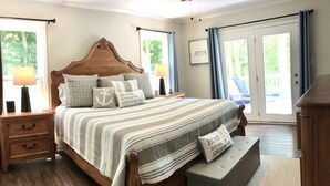 Een slaapkamer met een houten bed, gestreepte beddengoed en kussens met een nautisch thema.
