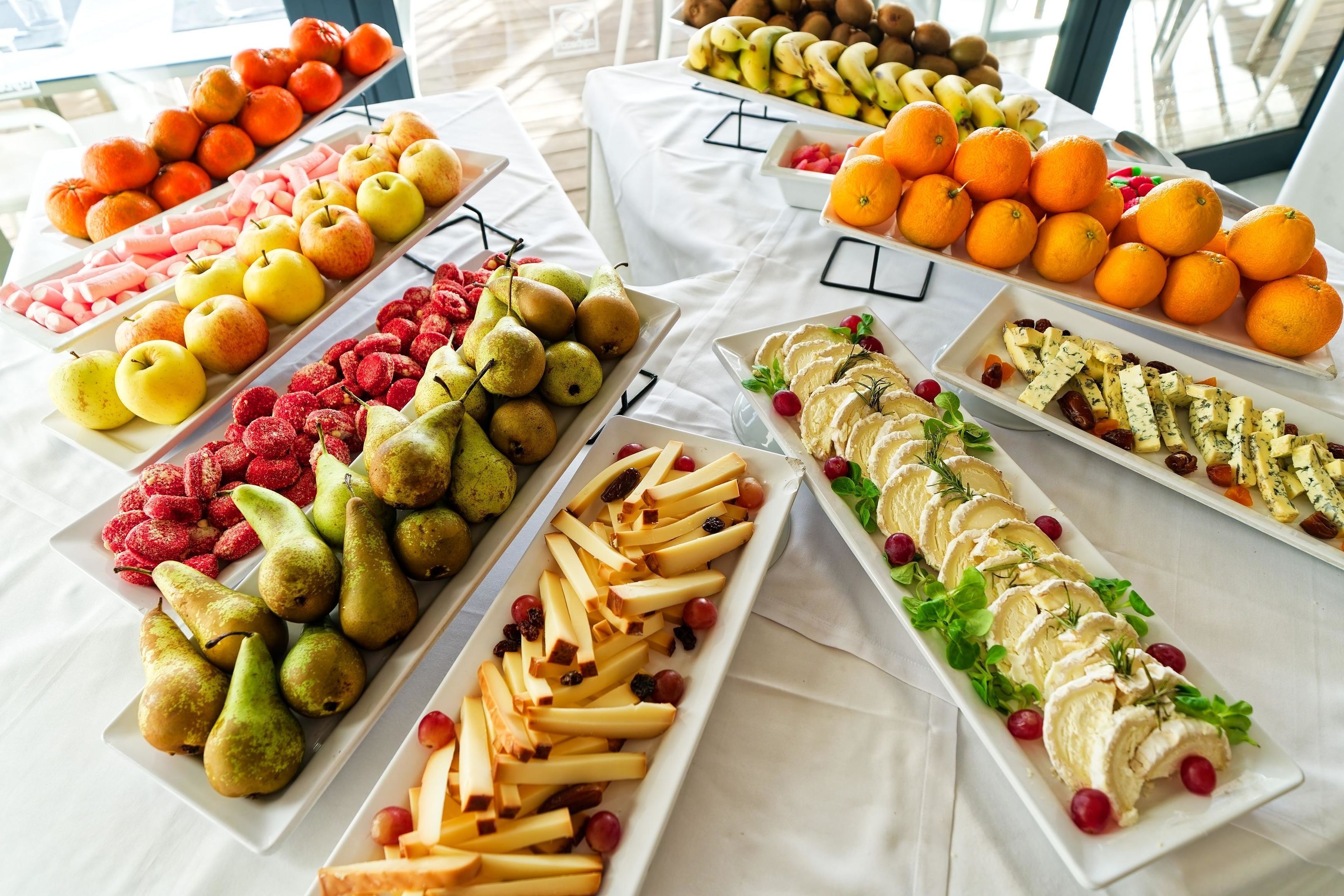 A buffet table with various fruits and cheeses.