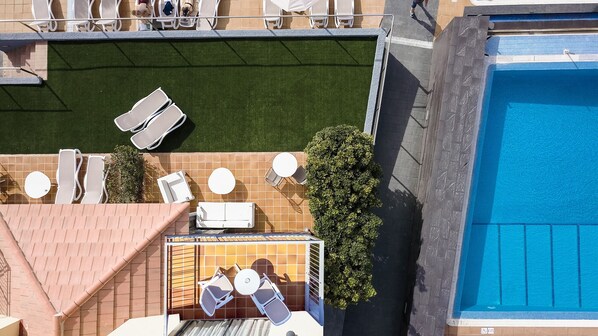 Un área de piscina en la azotea con múltiples tumbonas y una piscina grande.