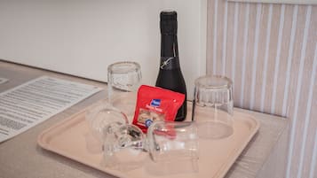 A tray with a bottle, a packet of snacks, and two glasses on a table.