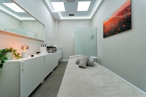 A modern bathroom with a skylight, a glass shower enclosure, a towel rack, and a painting on the wall. - Caybeach Meloneras (San Bartolomé de Tirajana)