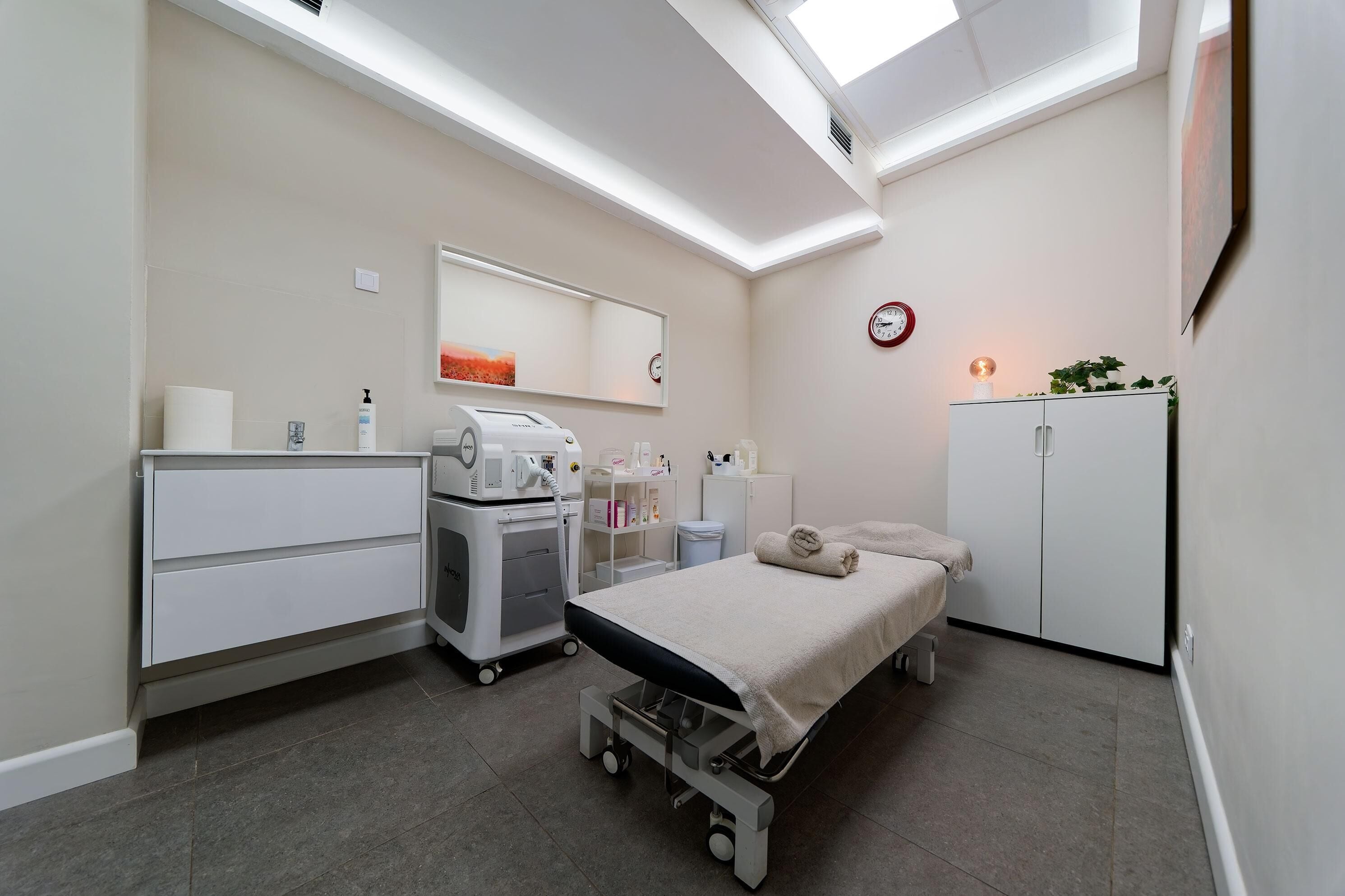 Een kamer met een bed, een bureau, een kast, een spiegel, een klok en een plafondlamp.