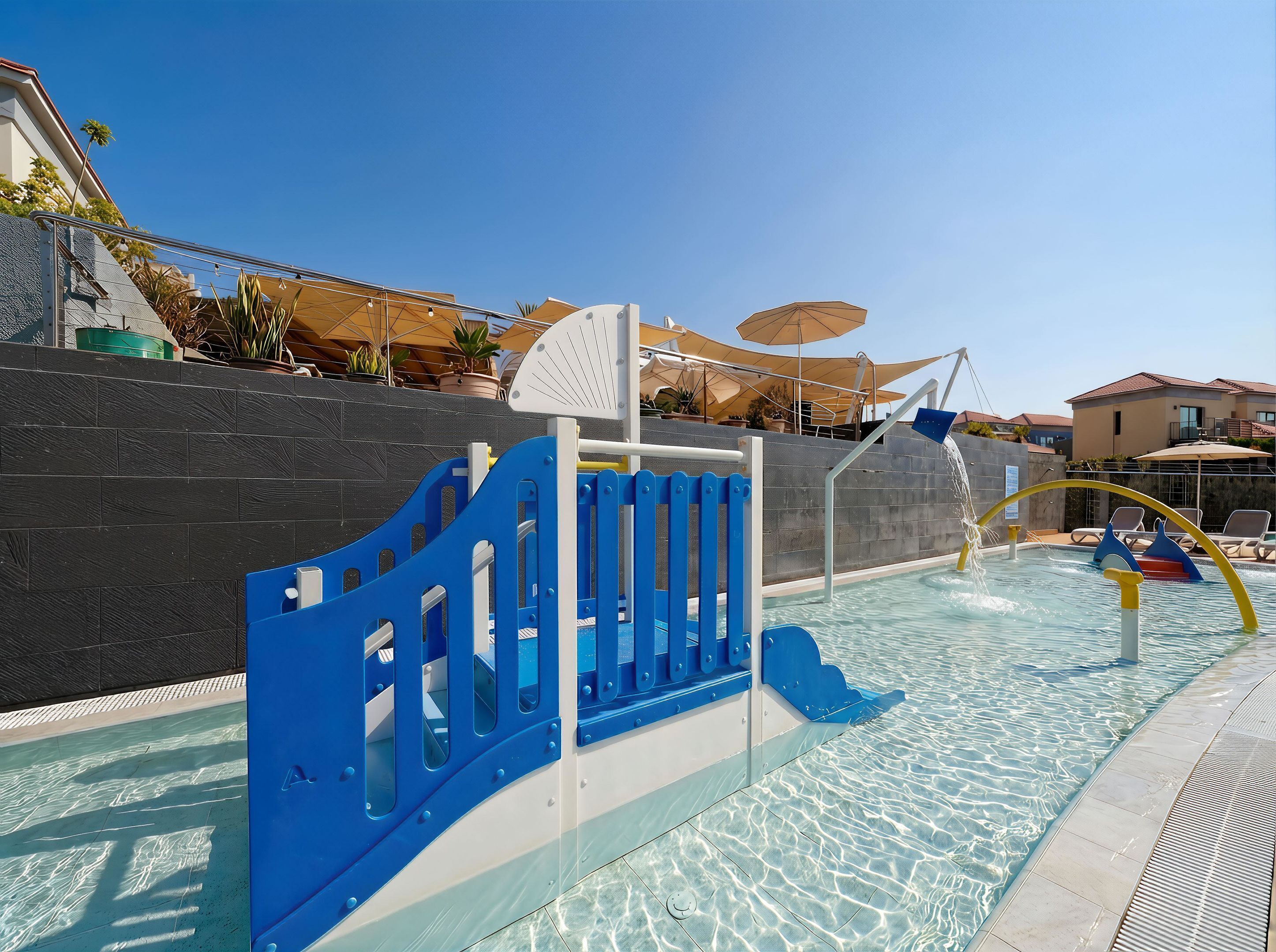 Un área de piscina con una puerta de seguridad azul, agua cristalina y sillas de descanso.