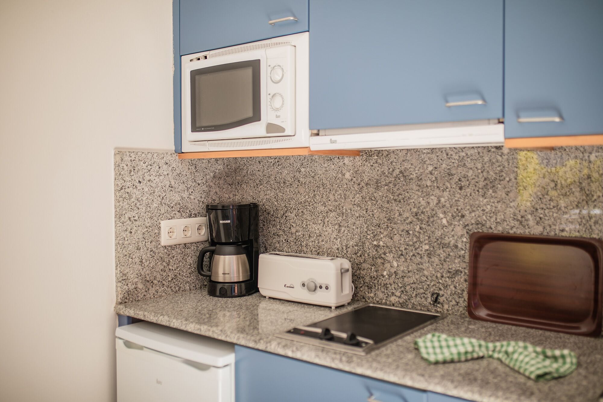Una cocina equipada con microondas, cafetera, tostadora y lavabo.