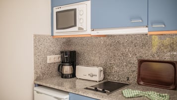 Una cocina equipada con microondas, cafetera, tostadora y lavabo.