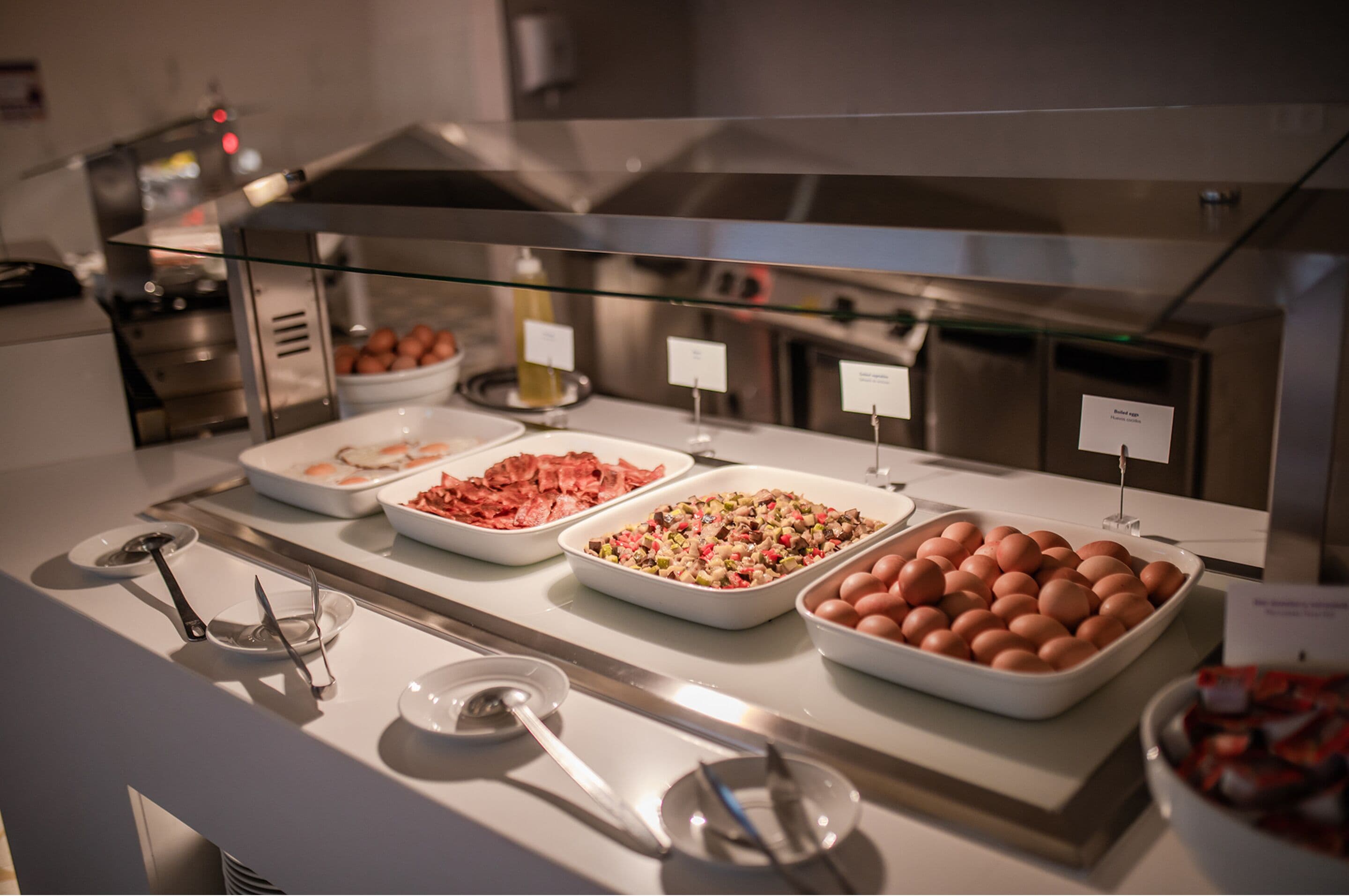 A buffet with various food items including eggs, bacon, and a salad.