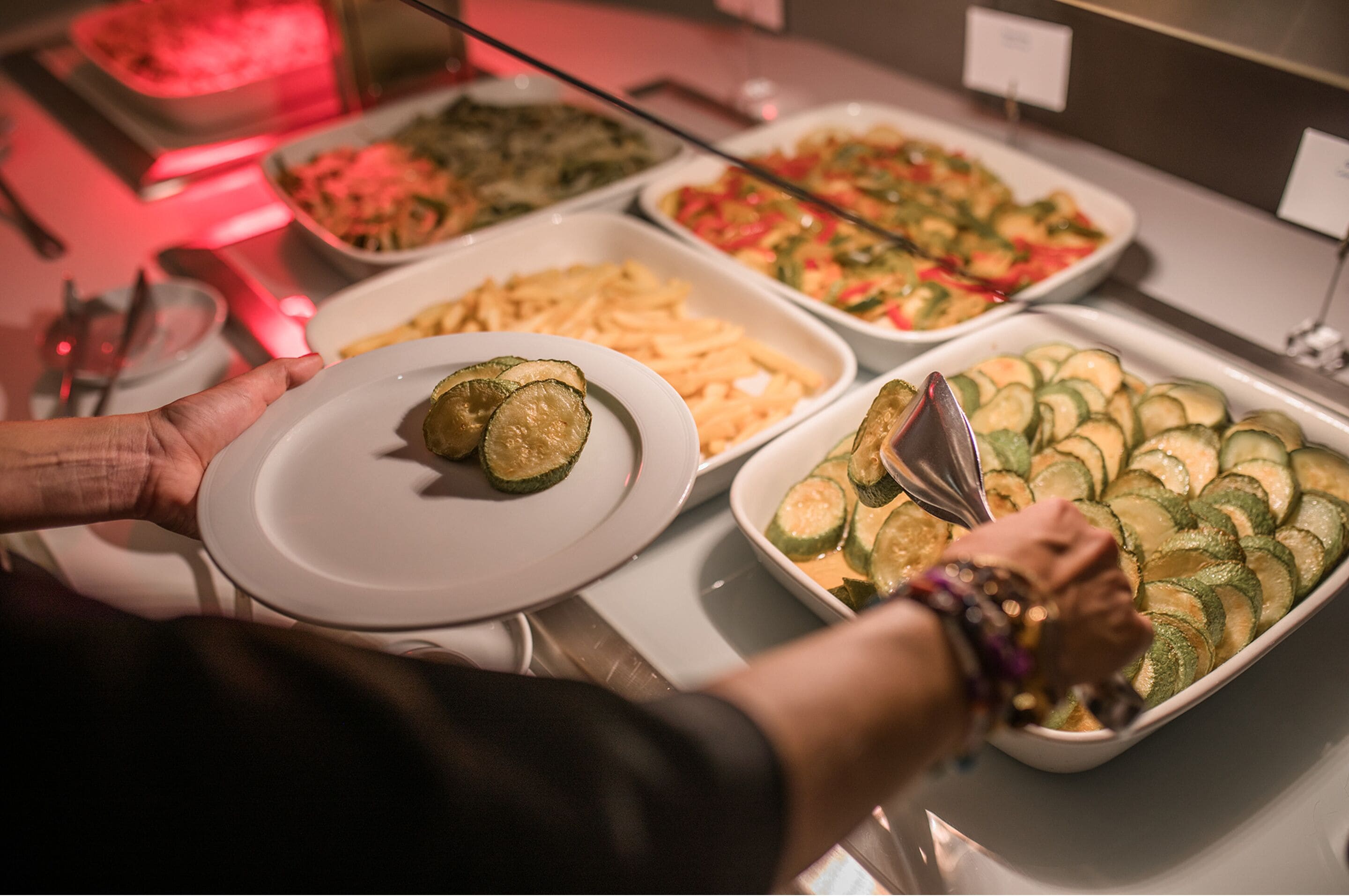 Un bufé con diversas opciones de comida, incluyendo pepinos en rodajas y un plato con dos pepinos.