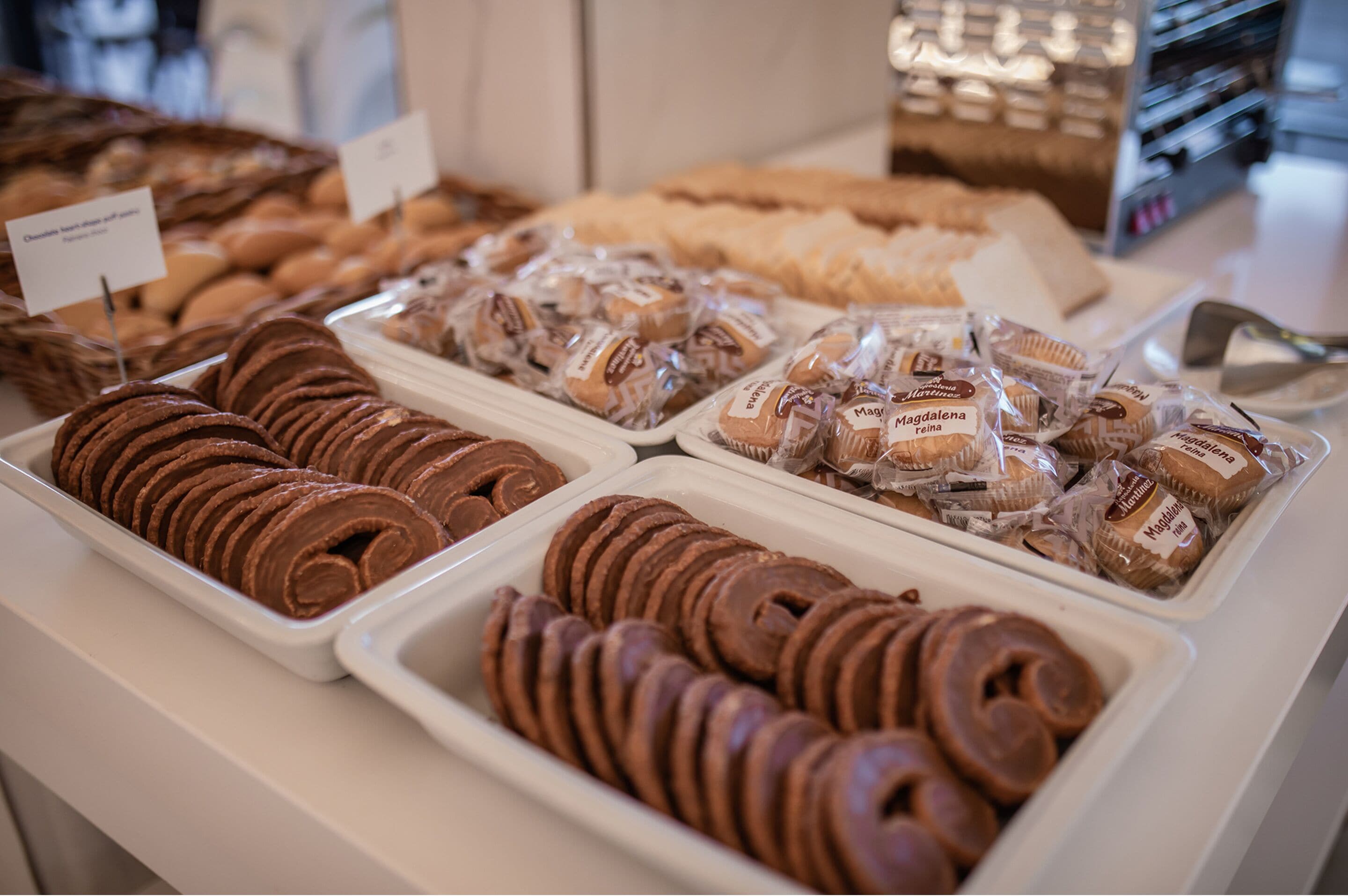 A display of various baked goods, including chocolate rolls and packaged pastries, arranged on a counter.