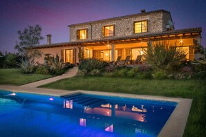 Une maison en pierre à deux étages, dotée d’une piscine, d’un espace extérieur aménagé et offrant une vue sur un ciel étoilé.