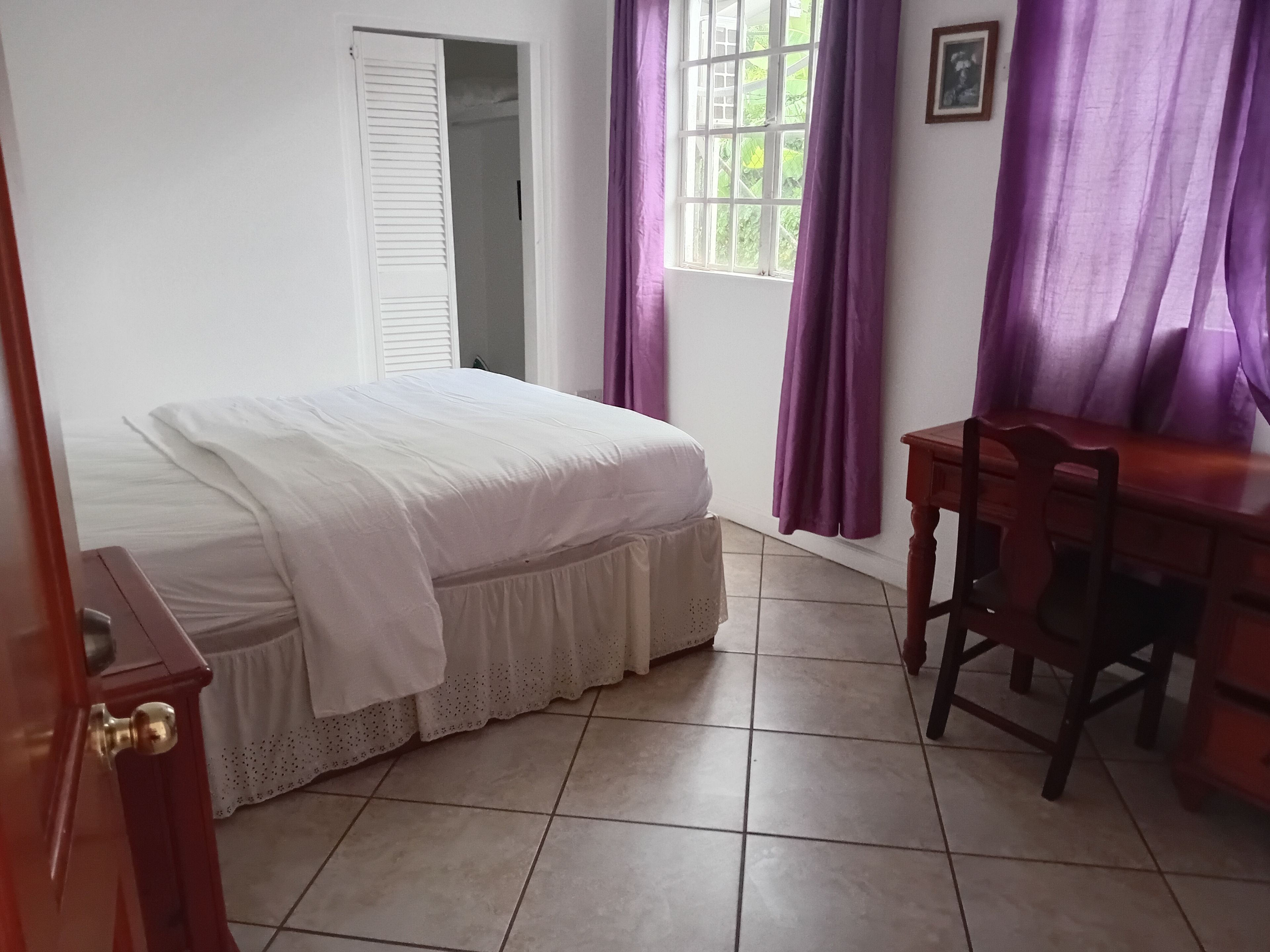 Un dormitorio con cama, escritorio y silla.