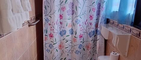 Un baño con inodoro, lavabo y cortina de ducha.