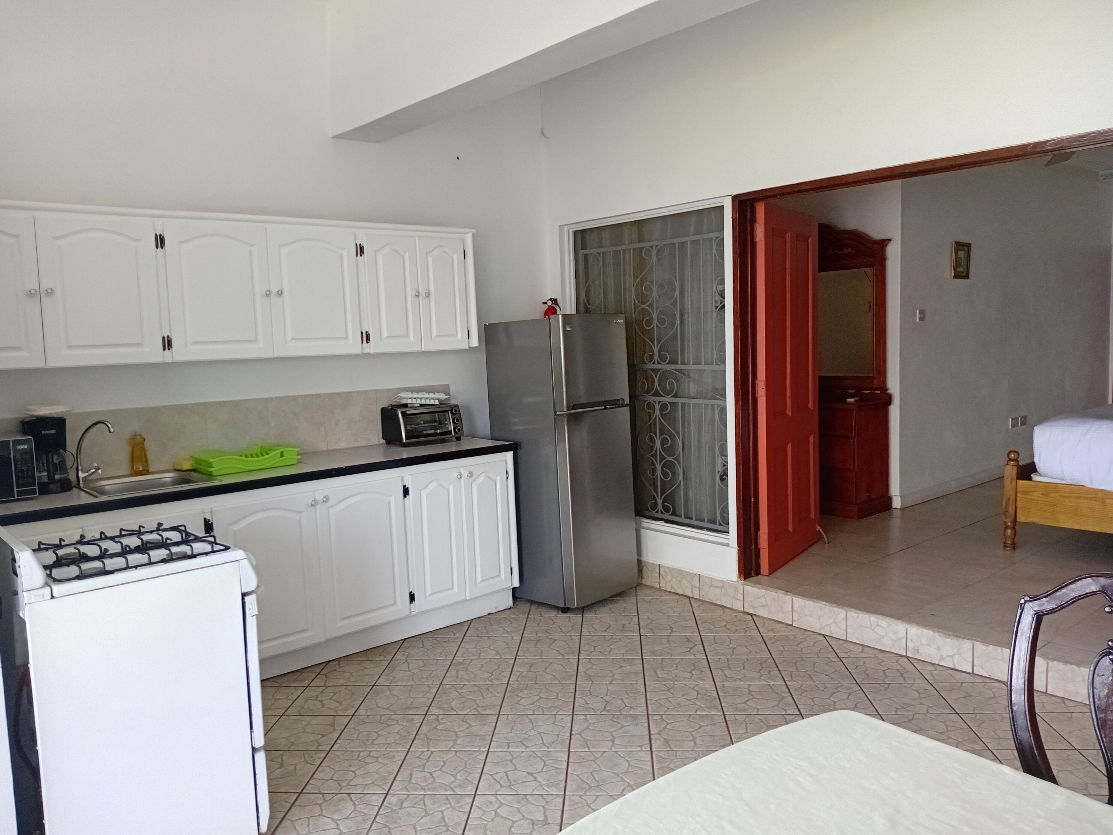 A compact kitchen with white cabinets, a gas stove, a toaster, and a refrigerator.