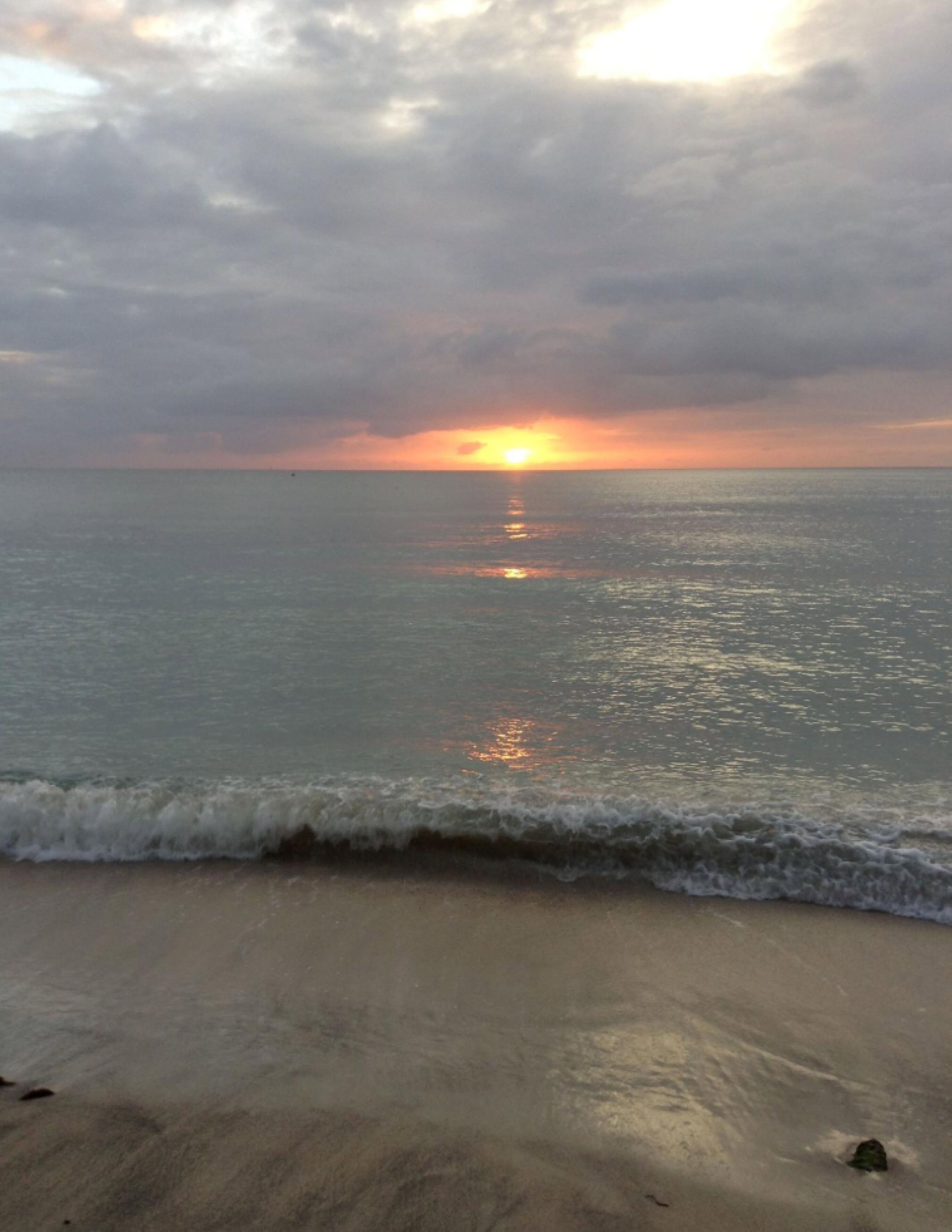 Una playa con un atardecer sobre el océano.