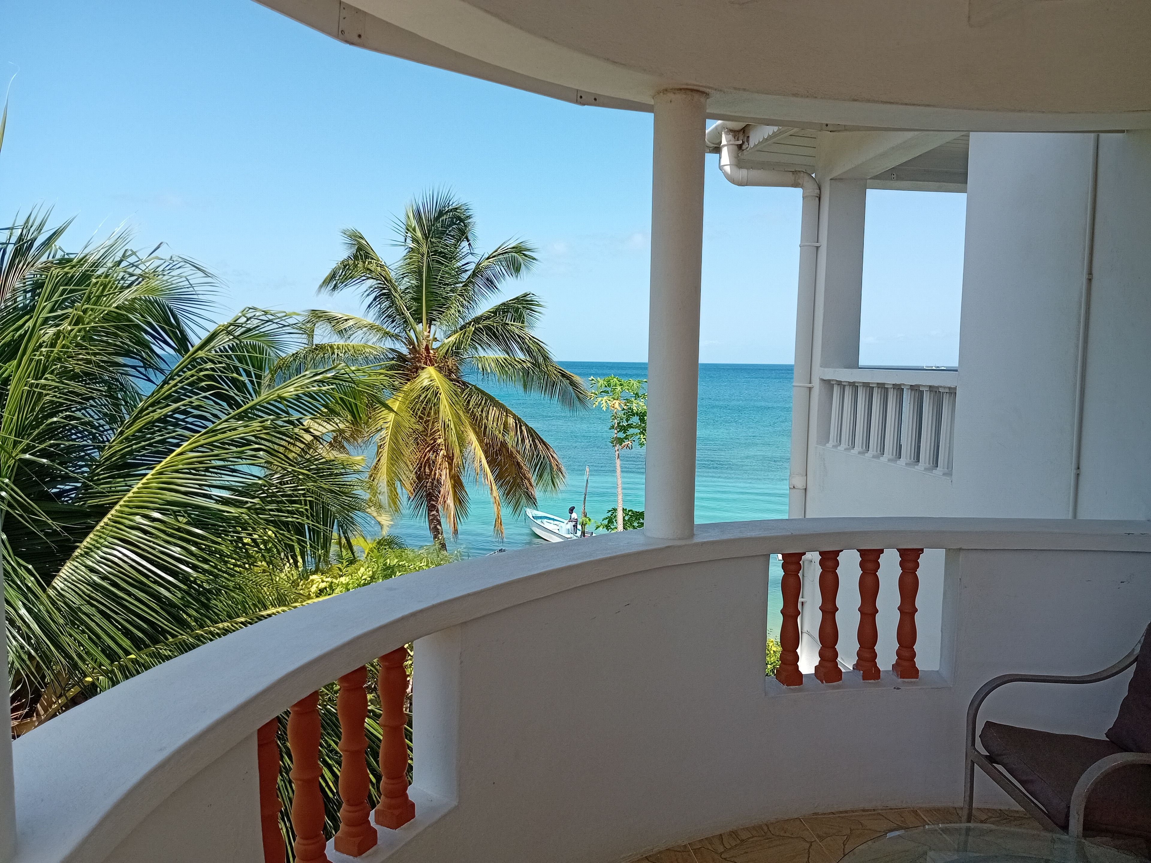 A balcony with a view of the sea and palm trees.