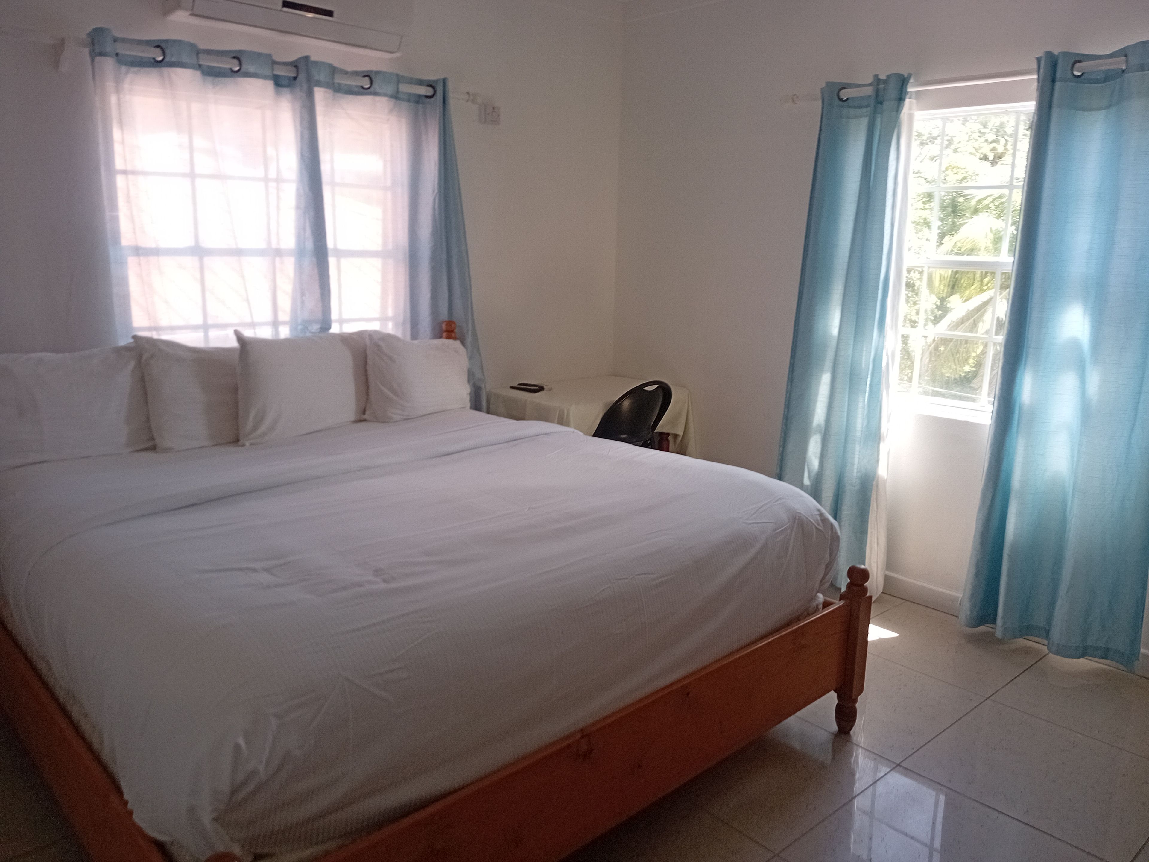 Una habitación con una cama grande, un escritorio y un ventanal con cortinas.