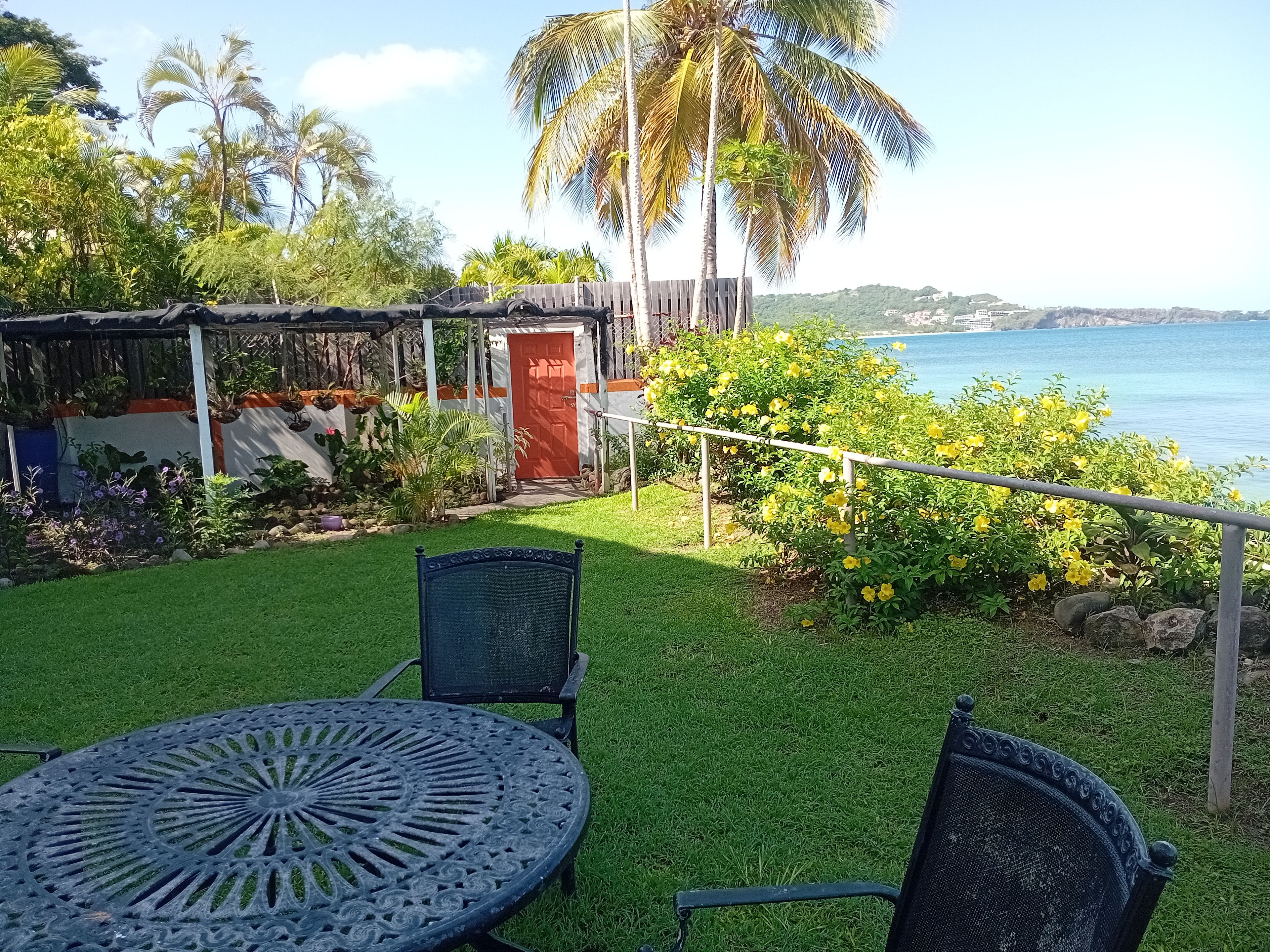 Eine Terrasse mit Tisch und Stühlen, ein Holzzaun und Blick auf das Meer.