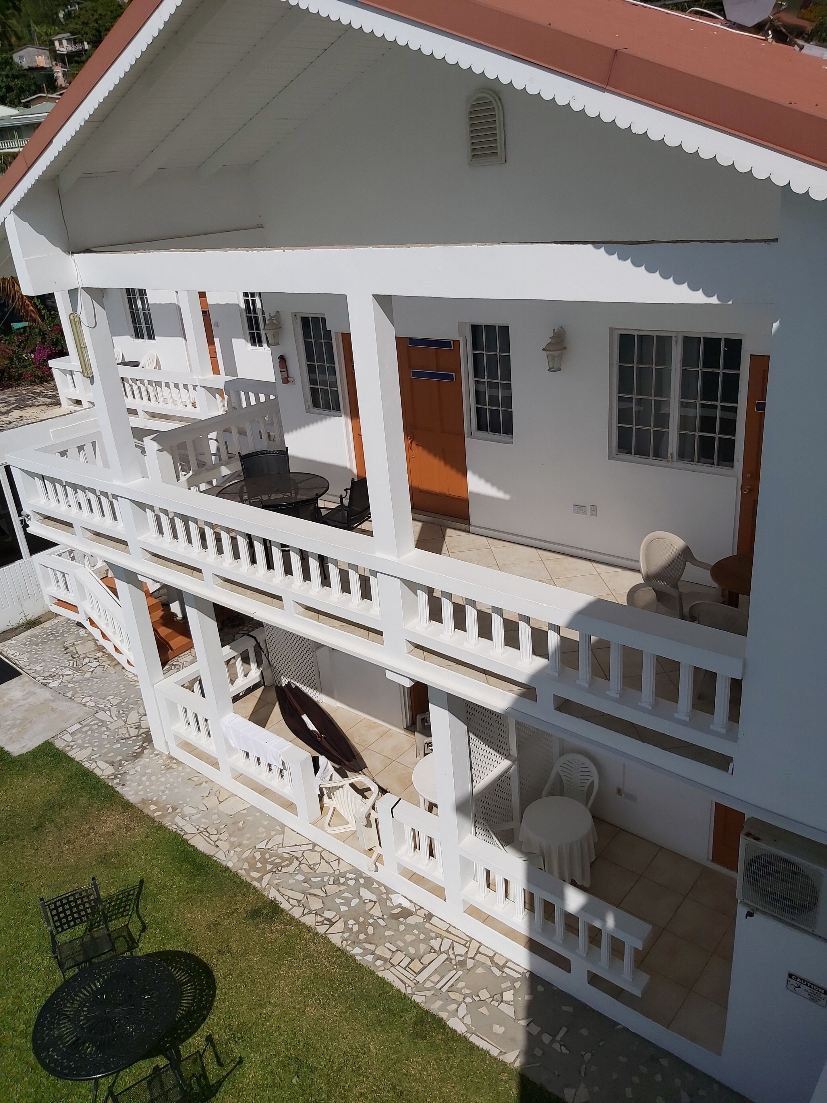 A two-story building with a balcony, outdoor seating, and a tiled patio.