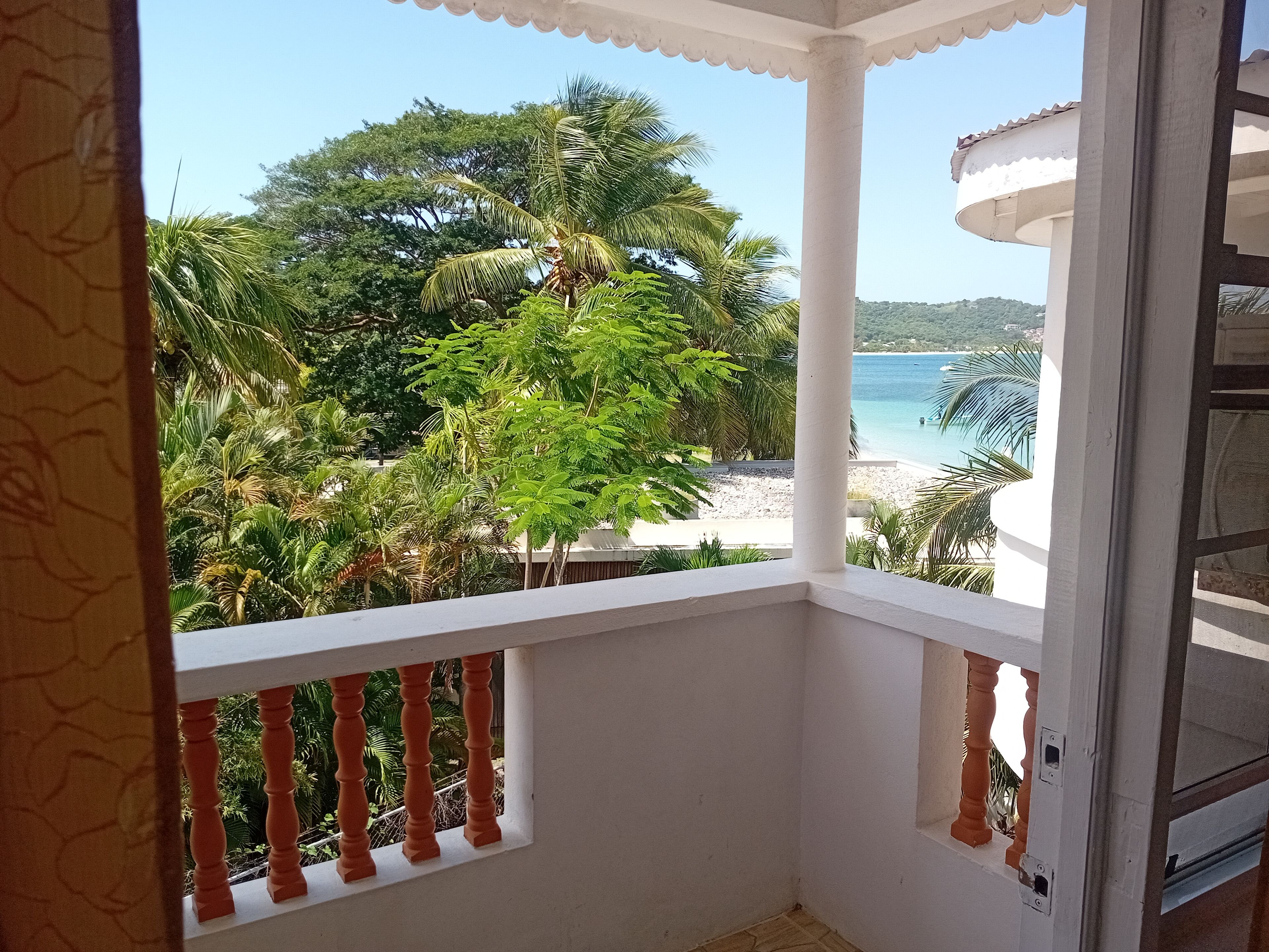 Un balcón con vista a una playa y palmeras.