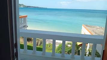 A view from a balcony with a railing, overlooking a calm sea and a distant shoreline.