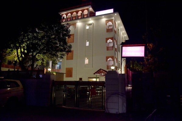 A multi-story building with a traditional architectural style, featuring arched windows and a balcony on the upper floors. - Hotel Triveni Residency Near SMS Stadium (Jaipur)