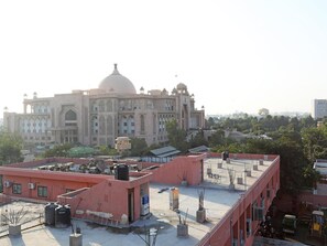 A large, historic building with a prominent dome and arched windows, surrounded by modern buildings and trees. - Hotel Triveni Residency Near SMS Stadium (Jaipur)
