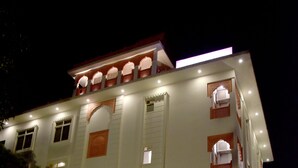 A multi-story hotel with a traditional architectural style, featuring arched windows and a covered entrance area with potted plants. - Hotel Triveni Residency Near SMS Stadium (Jaipur)