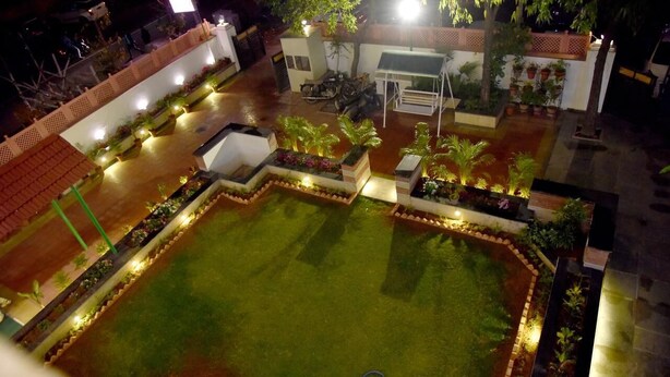A well-lit courtyard with a central lawn, surrounded by planters and seating areas. - Hotel Triveni Residency Near SMS Stadium (Jaipur)