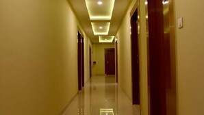 A long, well-lit hallway with a reflective floor, leading to multiple doors. - Hotel Triveni Residency Near SMS Stadium (Jaipur)