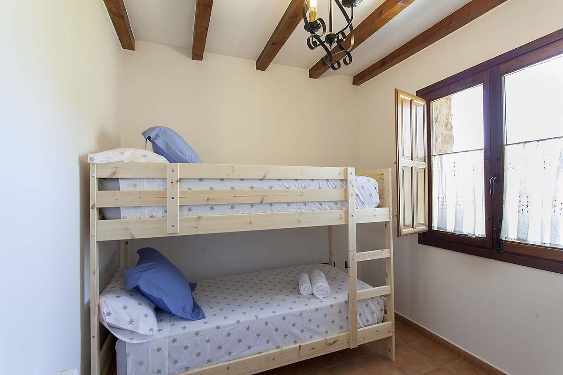 A bunk bed room with a window and wooden beams on the ceiling.