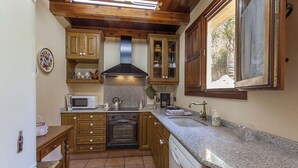 Una cocina compacta con armarios de madera, un microondas, un horno y un lavavajillas.