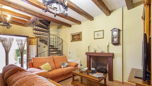 Una sala de estar con un sofá, una chimenea, un reloj y una escalera de caracol.