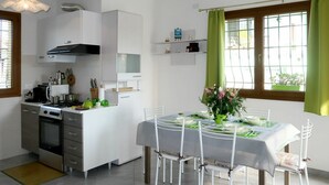 Una cocina moderna con armarios blancos, una estufa y un comedor con mesa para cuatro.