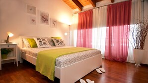 Un dormitorio con cama, mesita de noche, lámpara y planta en maceta.