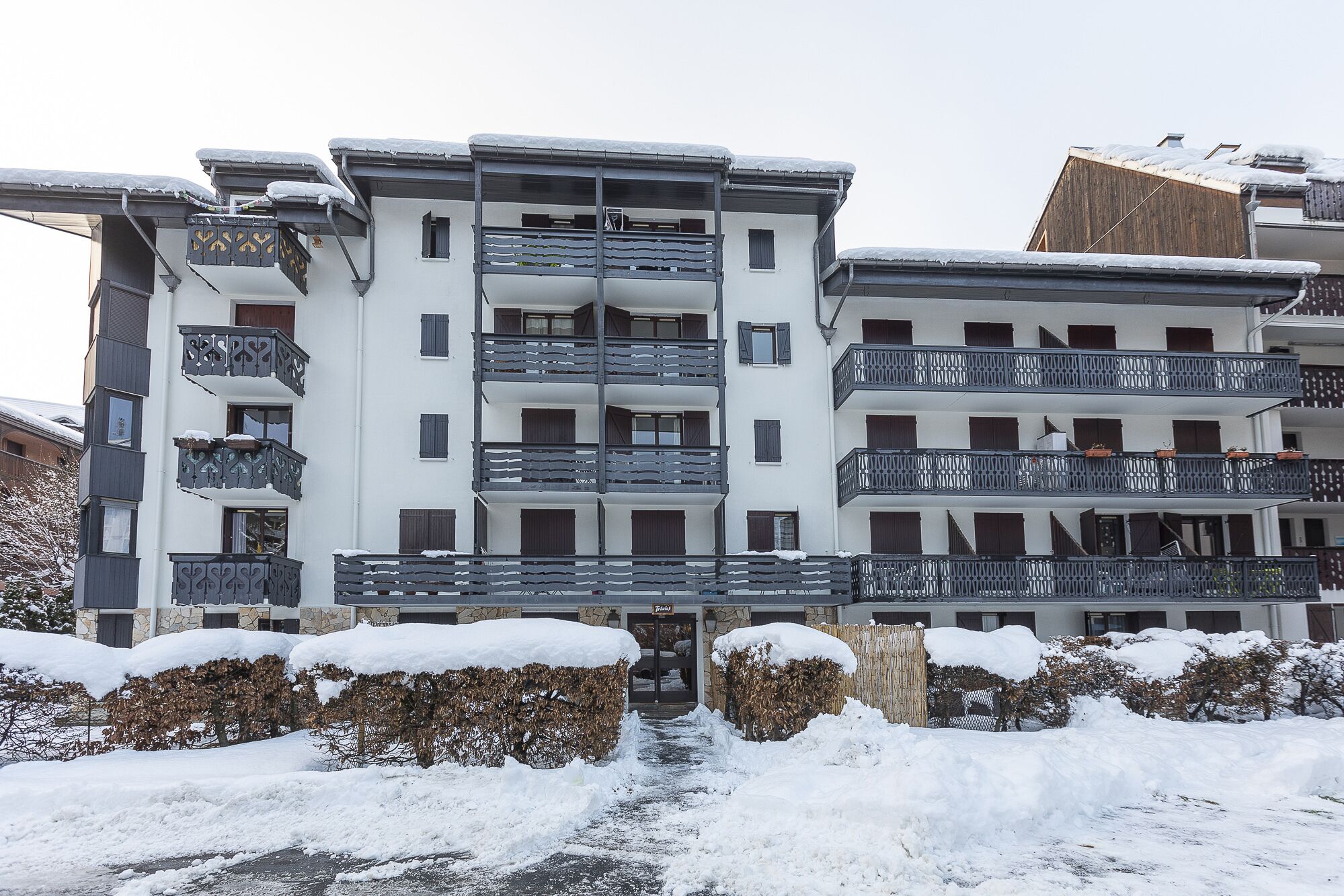A multi-story hotel with balconies, a stone facade, and snow-covered surroundings.