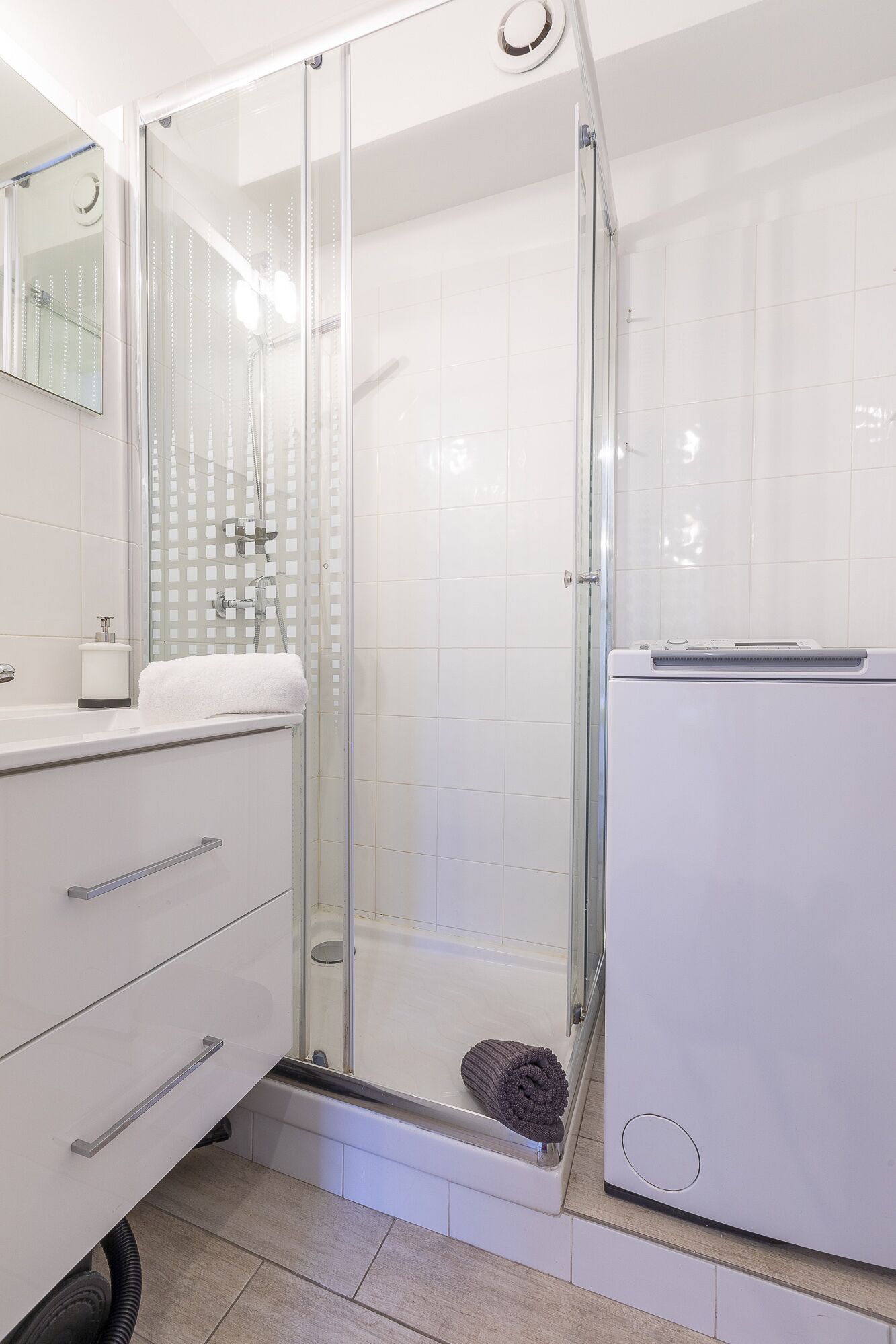 Une salle de bain moderne dotée d’une douche à parois de verre, d’un lavabo blanc et de toilettes intégrées.