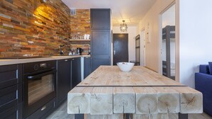 A modern kitchen with a wooden plank countertop, a built-in oven, and a black refrigerator. - Cham-Vue Apartment (Chamonix-Mont-Blanc)