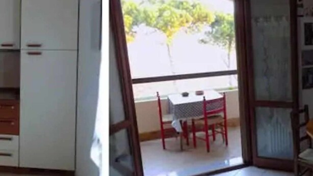 Ein Zimmer mit einer Schiebeglasdoor zum Außenbereich, der einen Tisch und Stühle bietet.